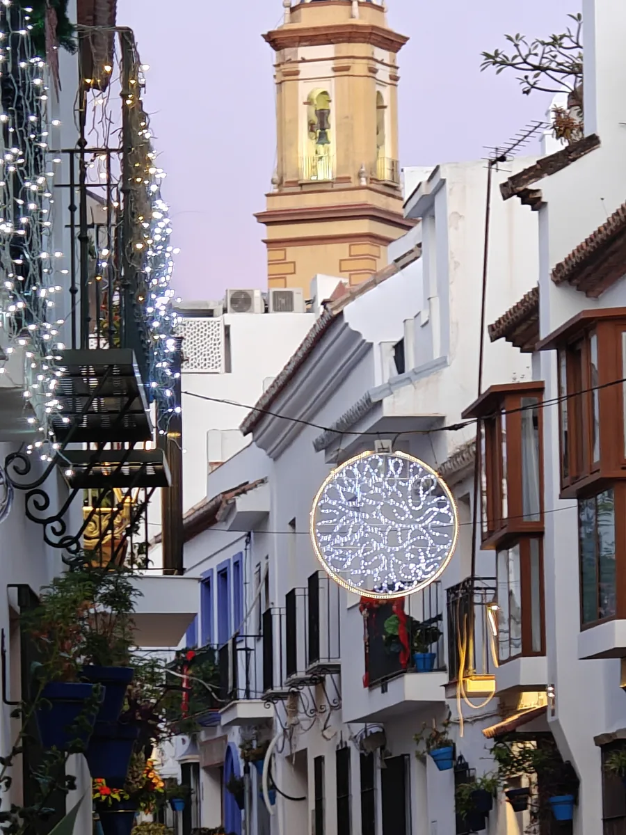 Street in the old town of Estepona at nightfall, illuminations and blue pots on the facades